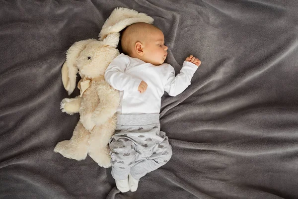 Baby sleeping with stuffed animal on blanket — Stock Photo, Image