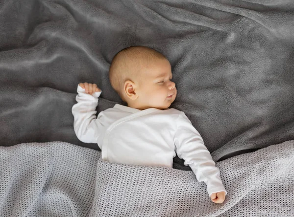 Малыш спит на сером одеяле — стоковое фото