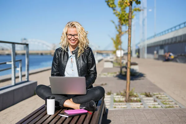 Kvinna sitter utanför med laptop i knäet — Stockfoto