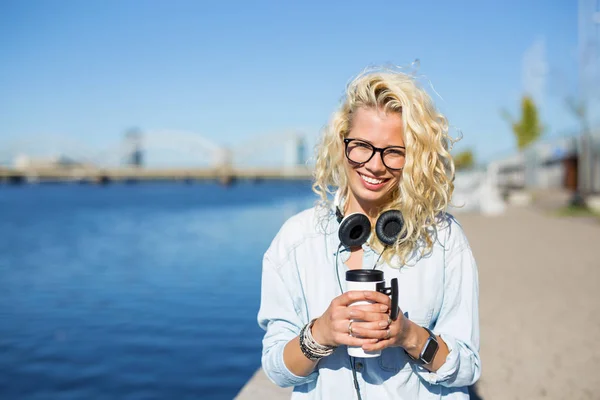 Hipster con le cuffie intorno al collo e la tazza di caffè in mano — Foto Stock