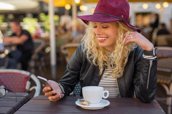 Женщина сидит в кафе и пользуется смартфоном — стоковое фото