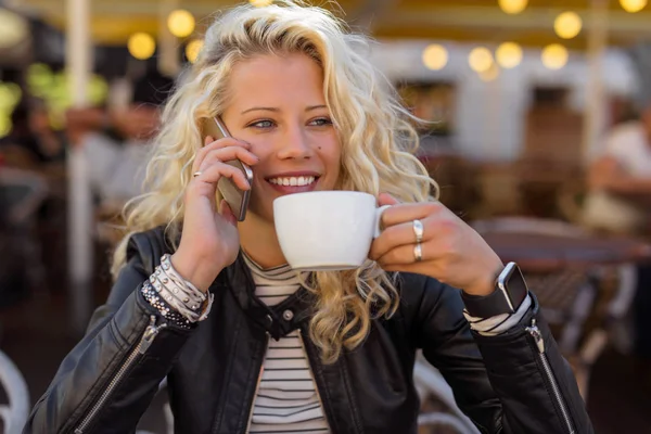 Kvinna dricker kaffe och pratar i mobiltelefon — Stockfoto