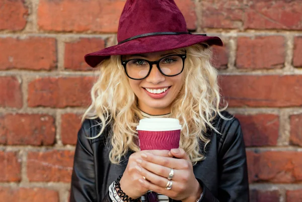 Ευτυχισμένη γυναίκα στέκεται και χαμογελαστός, με καφέ στα χέρια της — Φωτογραφία Αρχείου