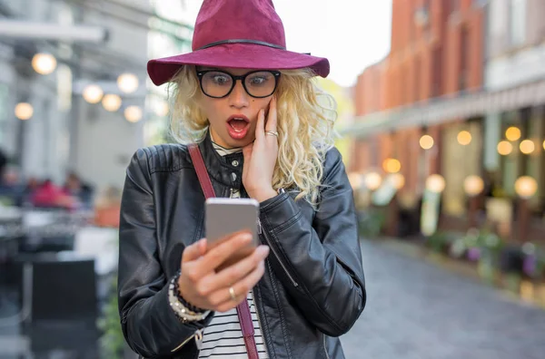 Mulher olhando para o telefone em choque — Fotografia de Stock