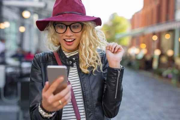 Mujer mirando su teléfono inteligente en agradable sorpresa —  Fotos de Stock