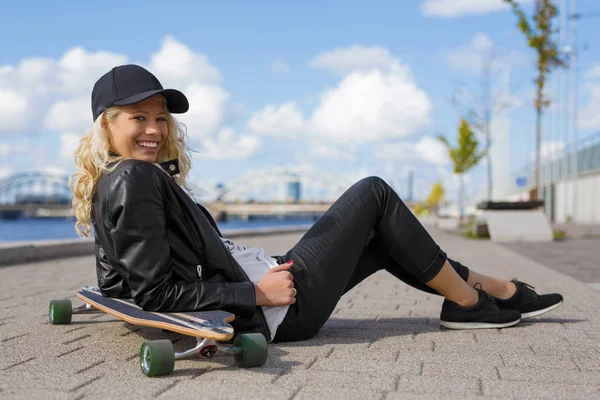 Mulher feliz com longboard sentado no chão — Fotografia de Stock
