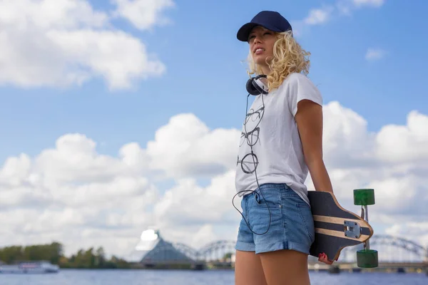 Woman holding longboard behind her back — Stock Photo, Image