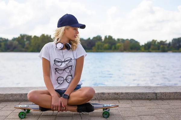 Mulher desportiva sentada no longboard — Fotografia de Stock