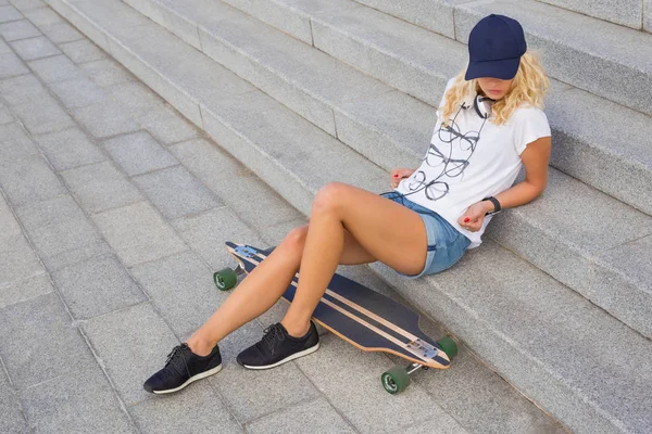 Mujer bonita sentada en escaleras con longboard — Foto de Stock