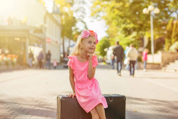 Kis lány ül a bőröndöt, és a gondolkodás — Stock Fotó