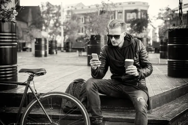 Immagine in bianco e nero di un uomo che prende un caffè e usa lo smartphone — Foto Stock