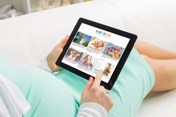 Беременная женщина читает детский блог на планшете — стоковое фото
