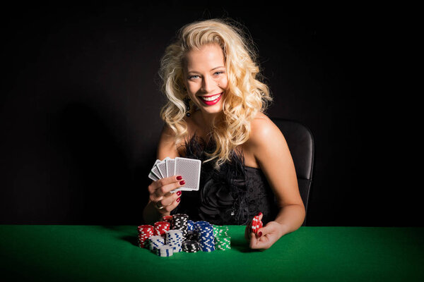 Woman sitting by the poker table with cards and chips in her hands