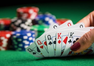 Poker oynayan ve kartlara bakan kişi