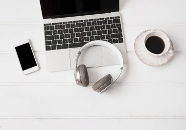 Kulaklıklar, dizüstü bilgisayar, cep telefonu ve fincan kahve