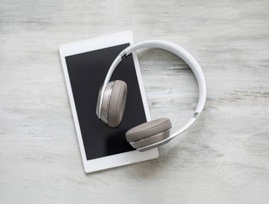 Headphones and tablet on wooden floor clipart