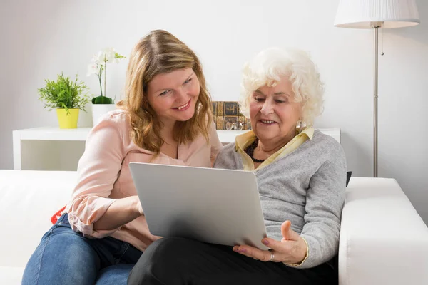 Granddaughter teaching grandma how to use laptop computer — Stock Photo, Image