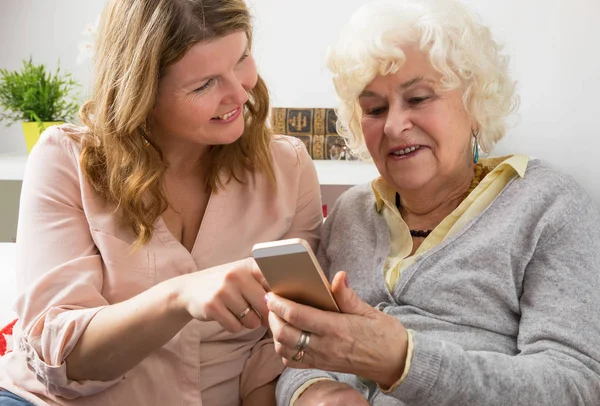 Granddaughter teaching grandma how to use smartphone — Stock Photo, Image