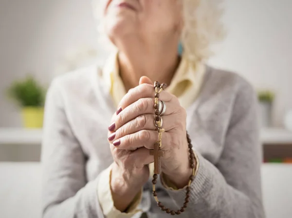 Бабушка молится с четками в руках — стоковое фото