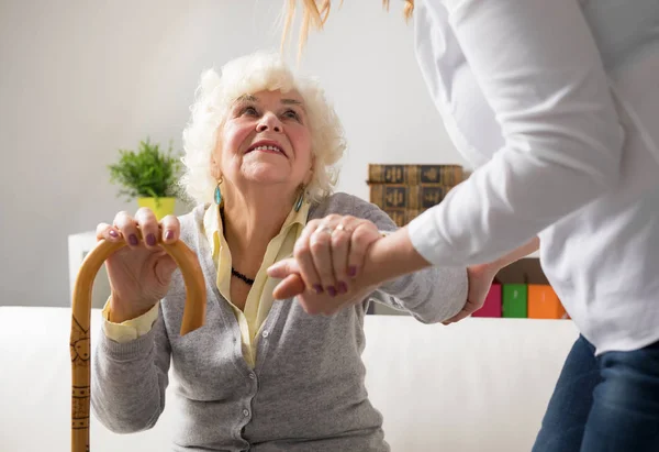 Sjuksköterska att hjälpa äldre kvinna att få upp — Stockfoto