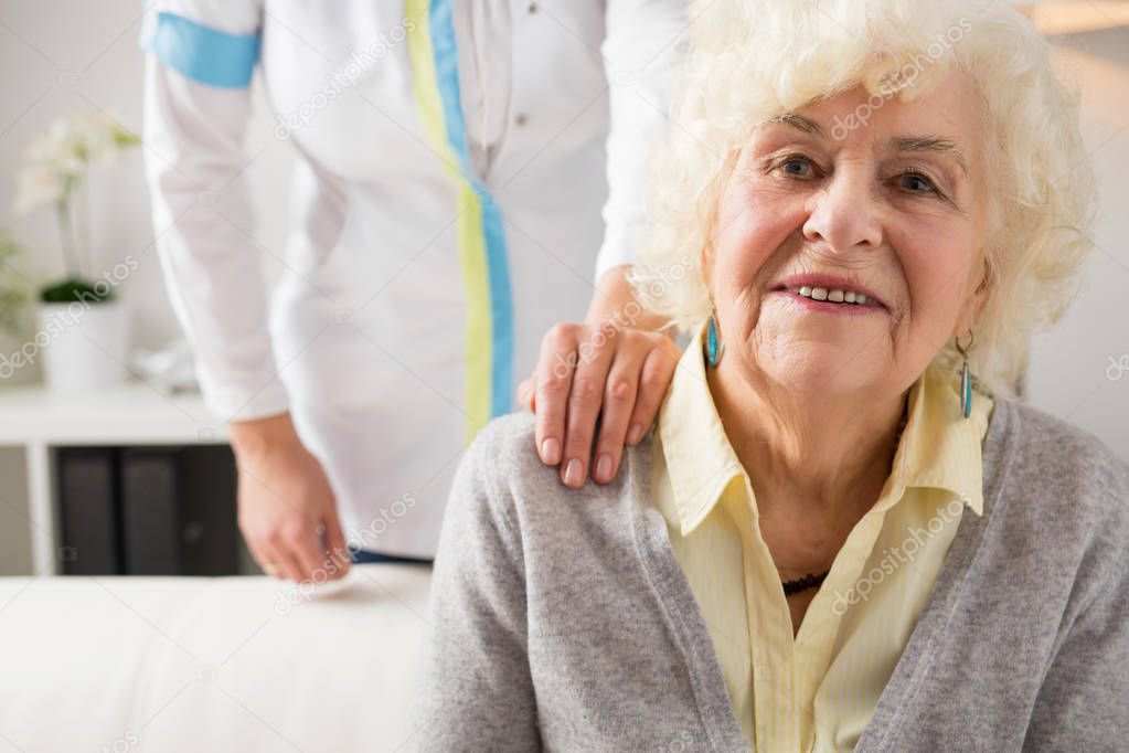 Nurse holding hand on elderly womans shoulder