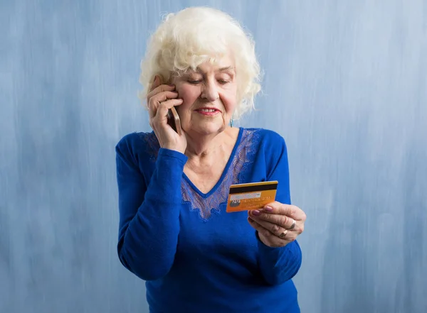 ผู้หญิงแก่พูดคุยทางโทรศัพท์และถือบัตรเครดิต — ภาพถ่ายสต็อก