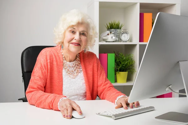 Working grandma at the office sitting by the computer — Stock Photo, Image