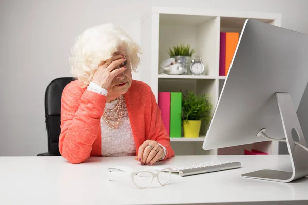 Older woman at the office having headache — Stock Photo, Image