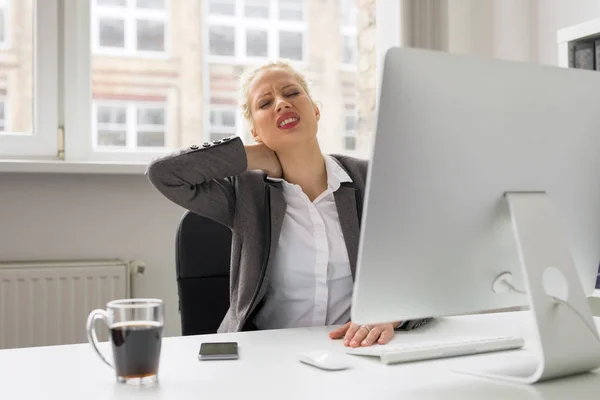 Frau im Büro hält sich vor Schmerzen am Hals — Stockfoto