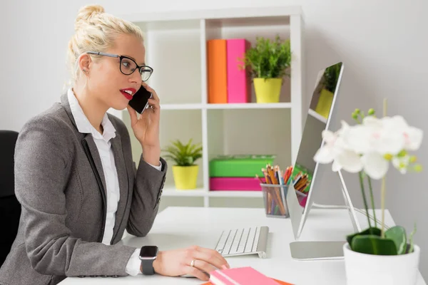 Woman talking on the phone and working on computer — Stock Photo, Image