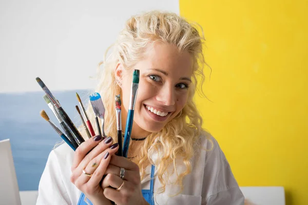 Artysta w jej studio, trzymając pędzle malarskie — Zdjęcie stockowe