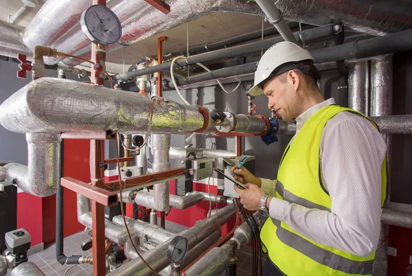 Man in helmet writing down measurements in heat and airconditioning system panel — Stock Image Man in helmet writing down measurements in heat and airconditioning system panel Stock Image