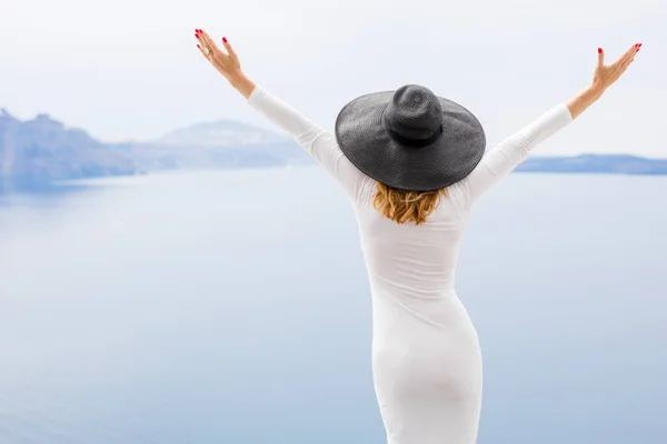 Mujer en vestido blanco y sombrero negro disfrutando de vacaciones — Foto de Stock