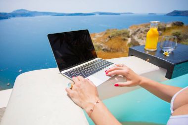 Havuzda dinlenme sırasında dizüstü bilgisayar kullanan kadın