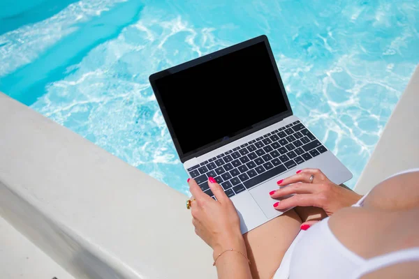 Ragazza in bikini che lavora con il computer portatile in piscina — Foto Stock