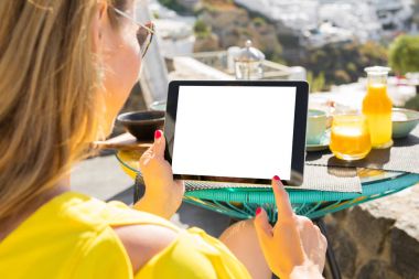 Kahvaltı, yatay ekran yönünü yaparken tablet bilgisayar kullanan kadın