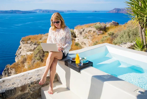 Havuz kenarında otururken dizüstü bilgisayar kullanan kadın — Stok fotoğraf