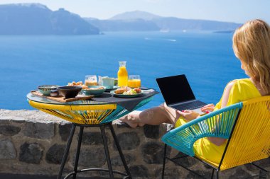 Kahvaltı yemek yerken dizüstü bilgisayar ile çalışan kadın