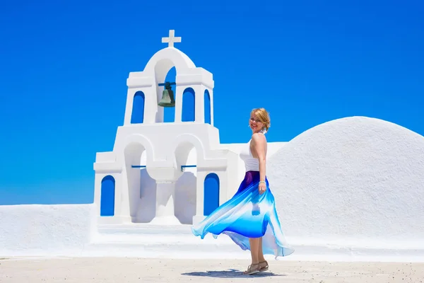 Mulher de vestido maxi longo em pé junto à igreja grega tradicional — Fotografia de Stock