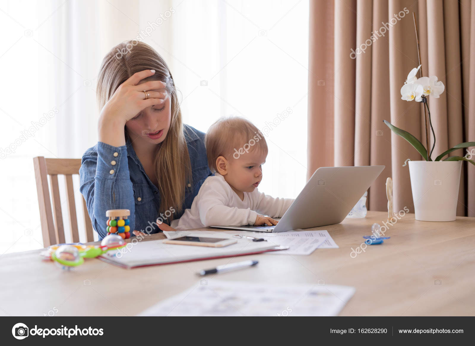 Tired working mom with child in her lap feeling exhausted Stock Photo