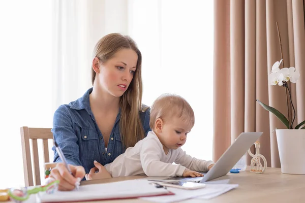 Mamma di lavoro con bambino in grembo e laptop — Foto Stock