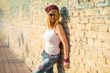 Tuğla duvara yaslanmış hipster kadın