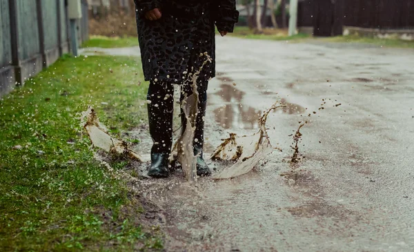 Pessoa em botas de chuva andando na poça — Fotografia de Stock