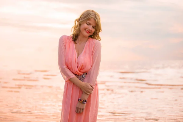 Schöne Frau in hübschem Kleid am Strand bei Sonnenuntergang — Stockfoto