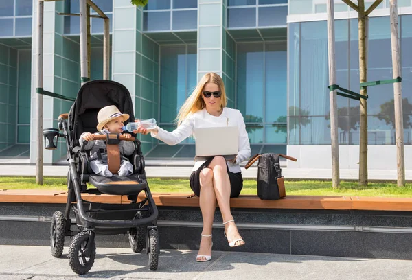 Mulher de negócios e mãe trabalhando no laptop com bebê no carrinho — Fotografia de Stock