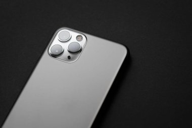 Koyu arkaplanda üçlü lens kamerası olan modern akıllı telefon.