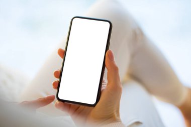 Evde akıllı telefonu tutan ve kullanan bir kadın. Boş beyaz ekranlı cep telefonu için model.
