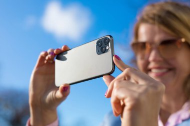 Kadın modern üç lensli kameralı telefonla fotoğraf çekiyor.