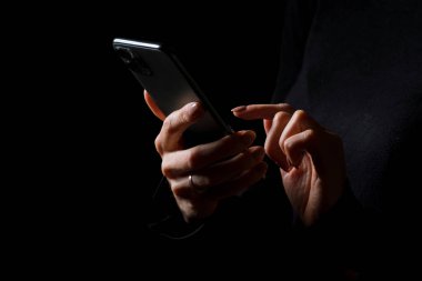 El ele tutuşan ve cep telefonunda yazan kişi, siyah arkaplanda izole edilmiş fotoğraf