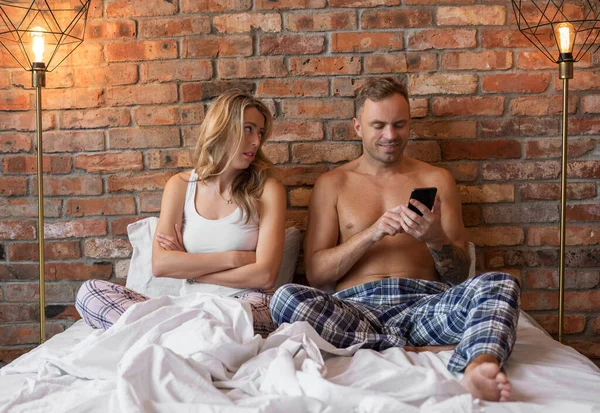 Hombre Presta Atención Mujer Cama Usando Teléfono Móvil Lugar —  Fotos de Stock